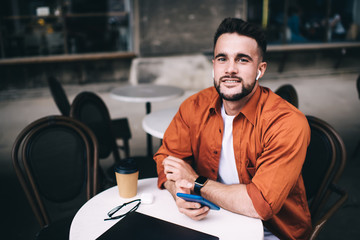 Cheerful man listening music in cafe