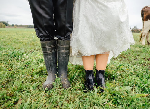 Groom and bride in rubber boots at countryside wedding in rainy weather