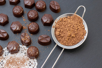 chocolate candies on a black background, cocoa powder. dark photo, mood.