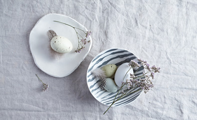 An arrangement of Easter eggs, ceramics and dried flowers on natural linen cloth. Copy space. Flat lay