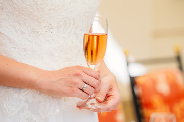 Women Bride holding glass with champagne and wedding ring on hand
