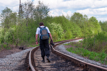 The railway path running through a line with a slightly blurred figure of a photographer looking for a new plot bright May day with a blurry foreground