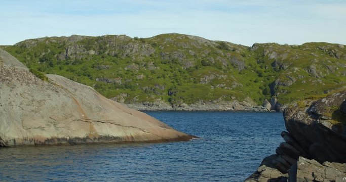 Lofoten, static shot of Nordic landscape. Summer with blue sky and calm lake with rocks.