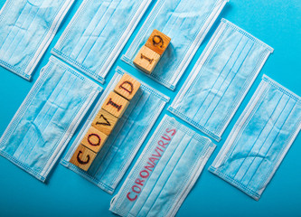 COVID - 19 cubes on medical masks blue surface. Corona Virus 2019 - nCOV.