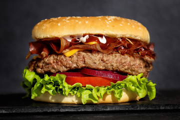 big hamburger with fresh lettuce, onion, tomato, cheddar cheese, beef and smoked meat