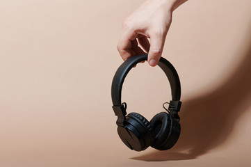 Hand hold black wireless headphones