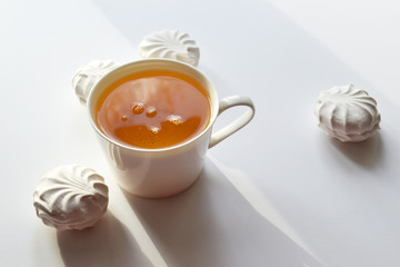 Exposition of sweet marshmallows with cup of tea on white background