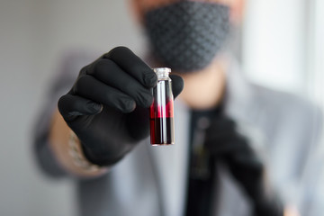 Young man holding test tubes with blood and antidote in his hand.