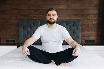 Fototapeta premium Handsome caucasian man meditating and mindful on his bed in bedroom
