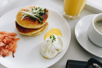 Close up of nutritious and tasty healthy pancakes and poached egg breakfast in bed on tray