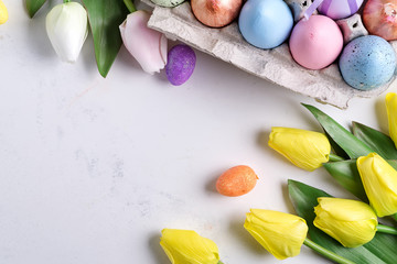 Fototapeta na wymiar Easter Eggs in box with yellow tulips on stone marble background. Easter background or easter concept.