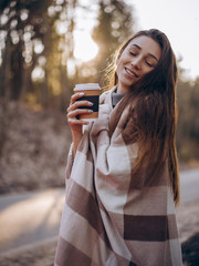 girl with cup of  coffee in a plaid in the sun