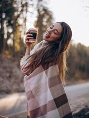 girl with cup of  coffee in a plaid in the sun