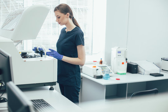 Careful lab technician working with centrifuge machine stock photo