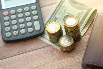 close up of stack of coin, cash and wallet on table.