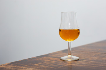 close-up of  whiskey tasting glass with whiskey held in a hand on a gray background