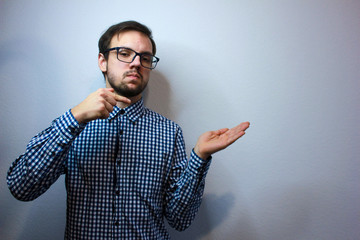 Closeup portrait happy young man looking to side while pointing at you, surprised by something someone isolated on gray wall background