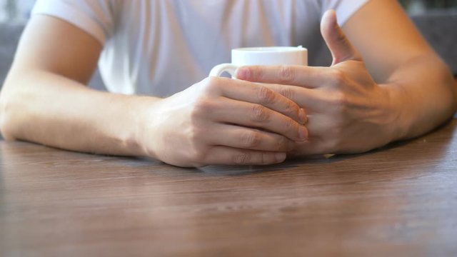 closeup. the man wears a wedding ring, sitting in a cafe.
