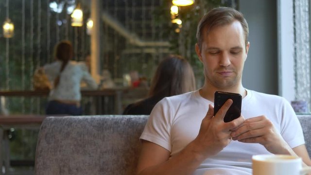 man takes off a wedding ring while sitting in a cafe. surrounded by girls