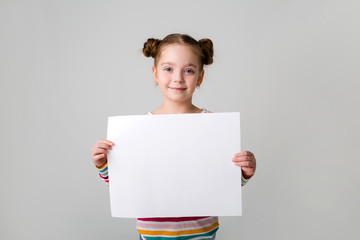 baby girl holding a white sheet.Cute little girl with a white sheet of paper.blue background.space...