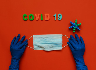 Medical mask in doctors hands with protective gloves. Red background. Coronavirus concept. Pandemic in the world.