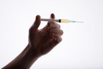 Close-up view of doctor holding syringe. White background. Hand with injection.