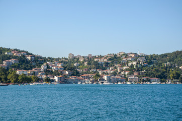 Hillside waterfront houses of the residential area at the Bosphorus Strait. Near the shore there are boats. Istanbul, Turkey.