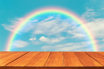 Wood table top on blue sky and rainbow. For display and montage products