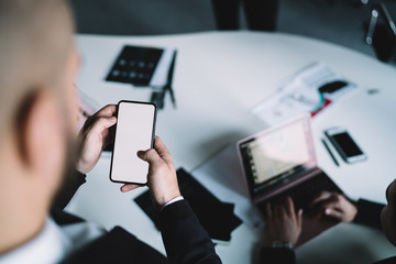 Crop executive browsing smartphone over table