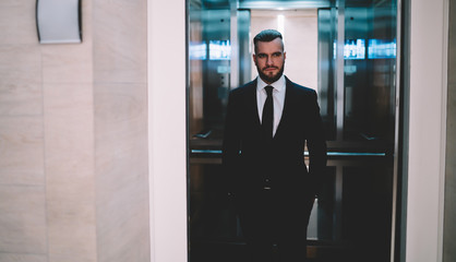 Pensive businessman standing in opened elevator and looking away