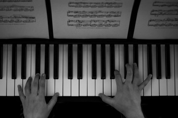 Fototapeta premium Black and white photography of hands playing piano and readingscores