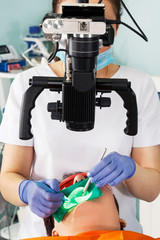 Dentist therapist works through a microscope