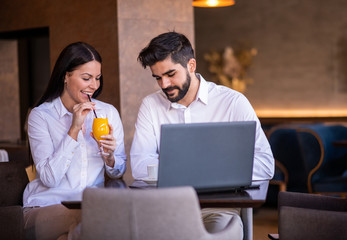 Business people looking, while the businesswoman is drinking orange juice.