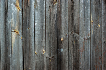 A very shabby old grey-brown fence, abandoned and forgotten, a background of wooden planks, in the style of rustic, grunge, old fashion