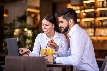 Businessman and businesswoman discussing a topic while they are both drinking orange juice.