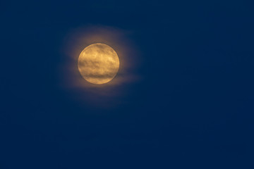Yellow full moon with halo against a dark blue sky