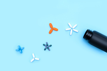 Pills collection in form of molecules of virus with plastic jar isolated on blue background. Vitamin deficiency, avitaminosis concept. Homeopathy cure treatment, Healthy Lifestyle. Disease protection