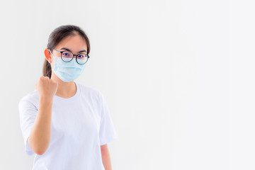 Portrait Asian young woman wears glasses and mask to protect against Coronavirus, girl show a fist encourage to fight contagious disease concept stop virus Covid 19 outbreak to win on white background