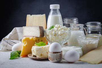 Fresh dairy products, milk, cottage cheese, eggs, yogurt, sour cream and butter on white table, black background