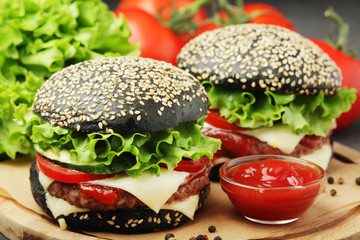 Two black burgers with vegetables and beef meat	