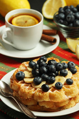Belgian waffles with blueberry and a cup of tea with lemon	