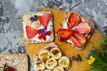 Breakfast with toaster and oat bread, buttered with butter, jam, strawberries and bananas on a concrete table.