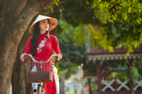 Portrait of Vietnamese girl traditional red dress,Beautiful young asian woman wearing Vietnam with bicycle