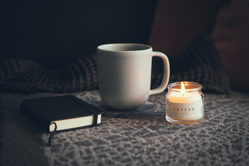 After busy work day resting at home, drinking cup of Chamomile tea just to feel to relax. Notebook for writing some thoughts, plans. Little candle with calming fresh cotton aroma. Natural light