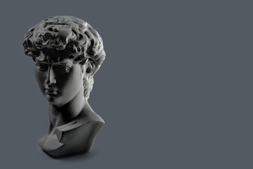 Gypsum statue of David's head. Michelangelo's David statue plaster copy on dark grey background with copyspace for text. Ancient greek sculpture, statue of hero