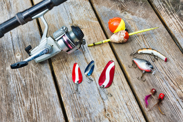 fishing rod, reel, lures, and bobbers on a wooden background