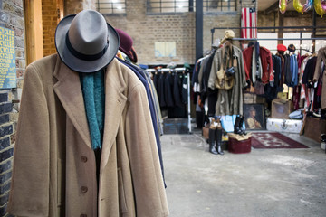 Spitalfields flea market. Woolen cashmere men's coat with felt hat on the background of rows with...