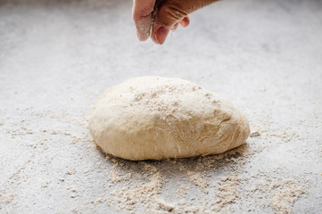 cook adding flour to a homemade pizza dough ball made in the kitchen