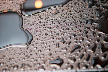 Drops of rain on the surface of black lacquered table with reflections. Texture