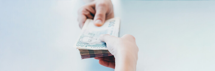 Illegal income. Bribery corruption. Woman receiving from man bundle of 500 ukrainian hryvnia bills.